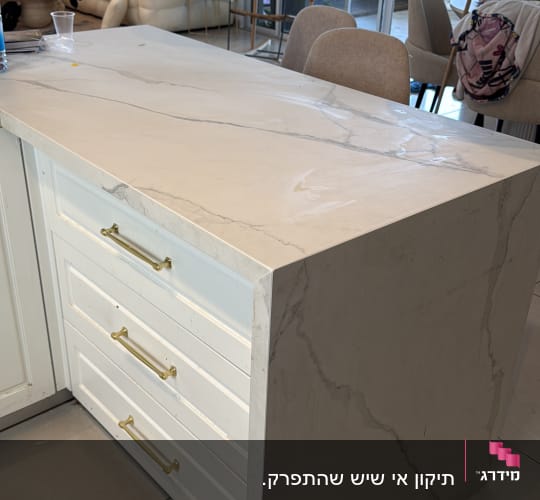 משטח שיש במטבח עם מגירות וידיות זהב